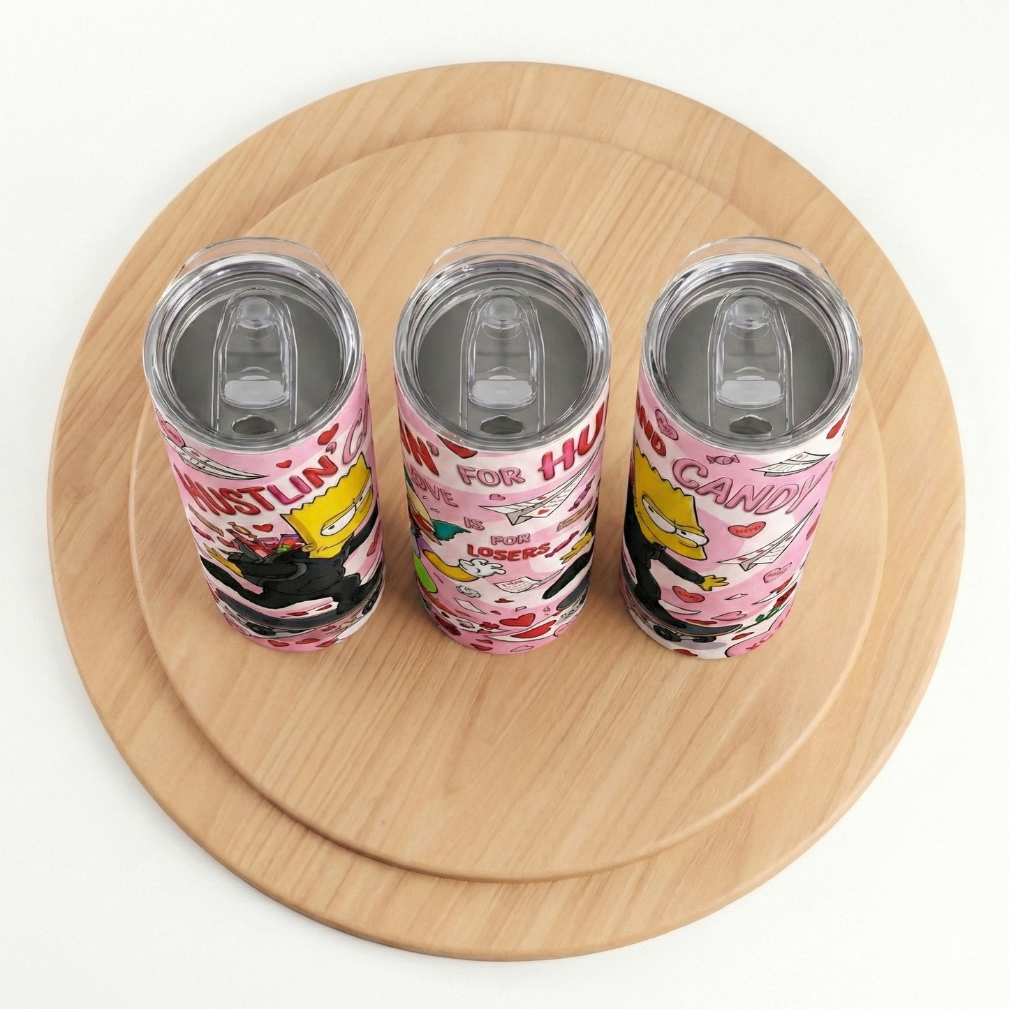 Three colorful tumblers with cartoon designs on a wooden surface