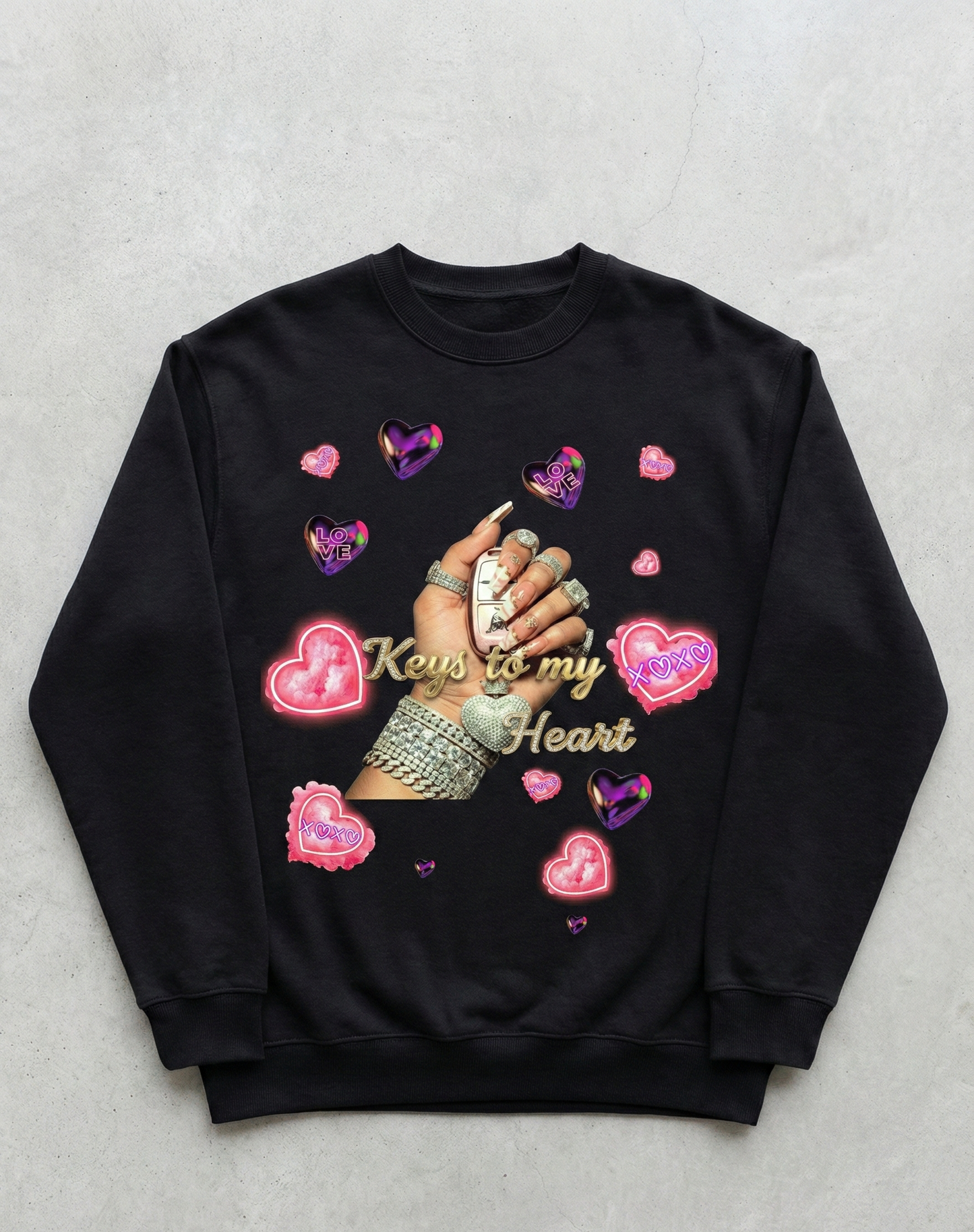 Black sweatshirt with hand holding keys design and heart shapes on a gray background