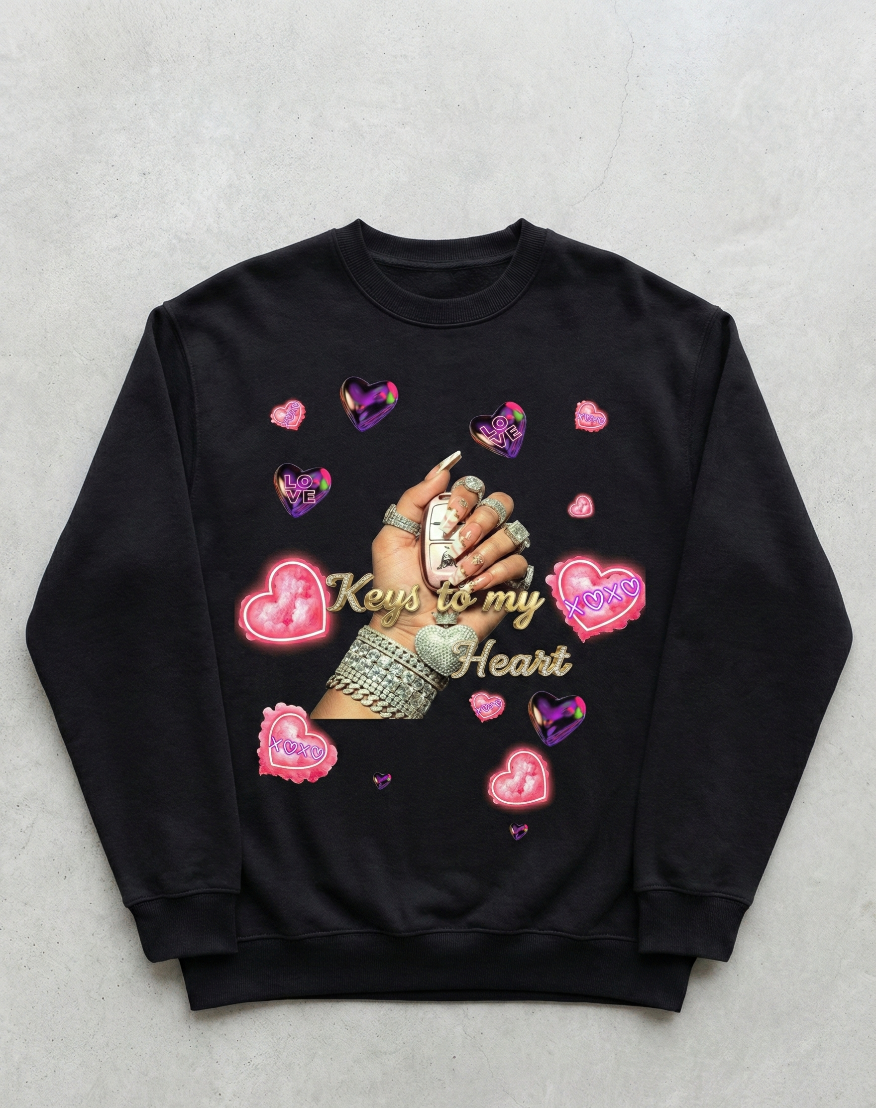 Black sweatshirt with hand holding keys design and heart shapes on a gray background