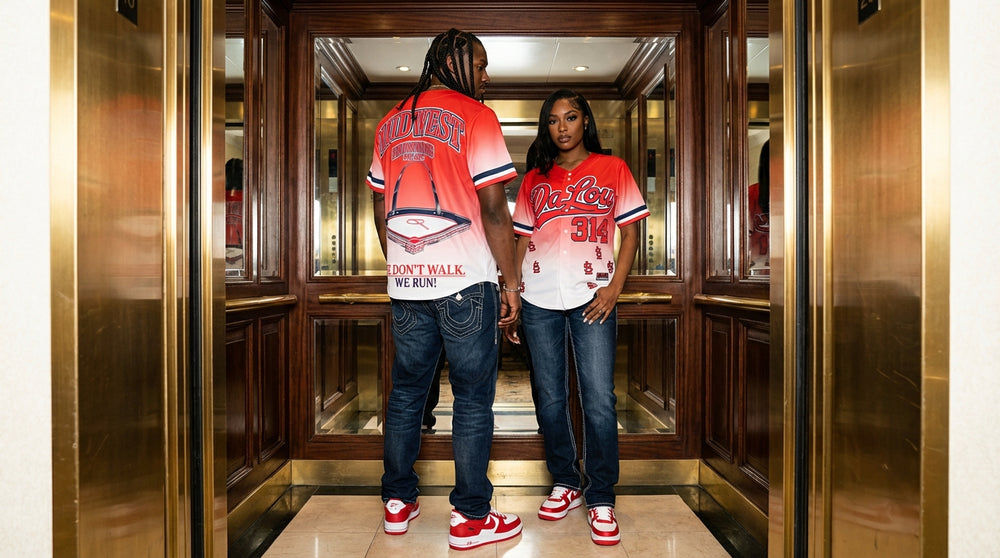 Two people wearing matching red and white baseball jerseys in an elevator.