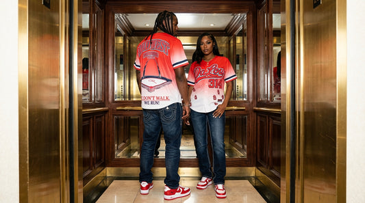 Two people wearing matching red and white baseball jerseys in an elevator.